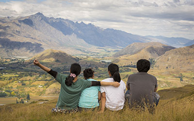 Family sitting at top of hill looking at mountain view